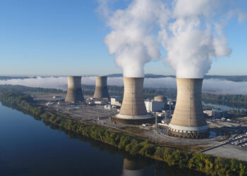 The Three Mile Island nuclear plant in 2019. The working cooling towers in the foreground are emitting water vapor. The dormant cooling towers are from Unit 2, which was permanently damaged in the 1979 accident. (Constellation Energy, CC BY-SA 4.0, via Wikimedia Commons)