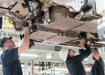 Workers install battery packs in a BMW X5 in South Carolina. A new battery plant under construction nearby will supply BMW factories. (BMW photo)