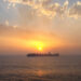 A container ship at sunset (XEON, CC BY 3.0, via Wikimedia Commons)