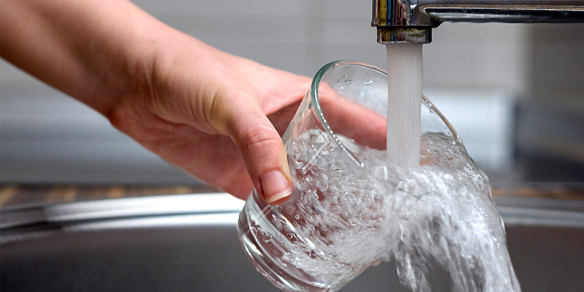 Water pours from a faucet into a glass (iStock image)