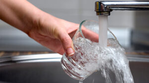 Water pours from a faucet into a glass (iStock image)