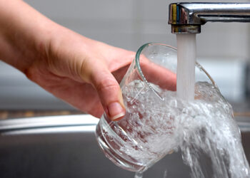 Water pours from a faucet into a glass (iStock image)
