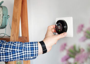 A wall thermostat is adjusted (iStock image)