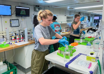 Aboard the RV Neil Armstrong, University of Miami graduate student Hope Elliott, left, prepares vials of seawater into which Saharan dust particles and volcanic ash were injected.. (Image courtesy of Hope Elliott/University of Miami)