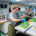 Aboard the RV Neil Armstrong, University of Miami graduate student Hope Elliott, left, prepares vials of seawater into which Saharan dust particles and volcanic ash were injected.. (Image courtesy of Hope Elliott/University of Miami)