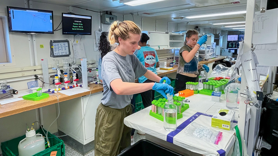 Aboard the RV Neil Armstrong, University of Miami graduate student Hope Elliott, left, prepares vials of seawater into which Saharan dust particles and volcanic ash were injected.. (Image courtesy of Hope Elliott/University of Miami)