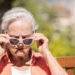 An elderly woman puts on sunglasses on a sunny day (iStock image)
