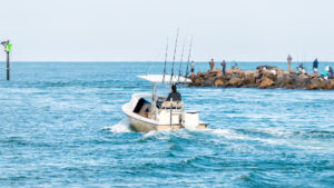 A boat heads out from Venice as people fish from nearby rocks (iStock image)