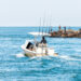 A boat heads out from Venice as people fish from nearby rocks (iStock image)