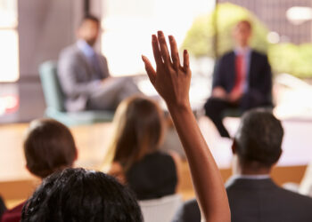 A woman raises her hand to ask a question (iStock image)