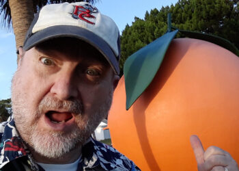 Craig Pittman poses by a giant replica orange (Photo courtesy of Craig Pittman)