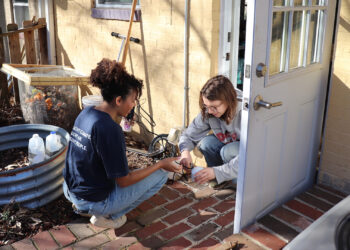 Daisha Wall, left, community science program manager at CleanAIRE NC, helps a community member set up an air quality monitor. The Trump administration has canceled environmental justice-related grants, including one CleanAIRE NC received to install air quality monitors. (Courtesy of CleanAIRE NC)