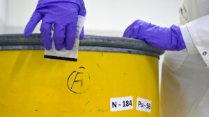 A wipe sample is taken to measure contamination levels on the outside of a waste drum. (IAEA Imagebank, CC BY 2.0, via Wikimedia Commons)