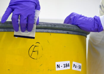 A wipe sample is taken to measure contamination levels on the outside of a waste drum. (IAEA Imagebank, CC BY 2.0, via Wikimedia Commons)