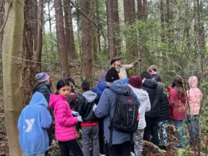 Sky Hawk Bressette teaches a group of fifth graders about removing invasive English holly at Lowell Park in Bellingham, Washington. (Allison Greener Grant via Grist)