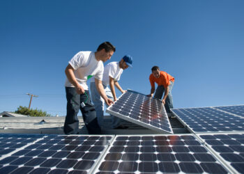 Workers install solar panels on a rooftop (iStock image)