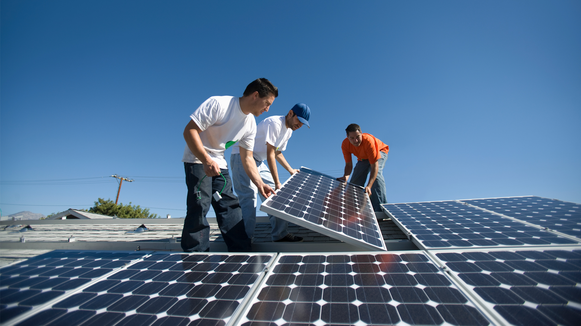Workers install solar panels on a rooftop (iStock image)