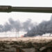 A Kuwaiti oil field set afire by retreating Iraqi troops burns in the distance beyond an abandoned Iraqi tank following Operation Desert Storm. (U.S. Navy; Public domain; via Wikimedia Commons)
