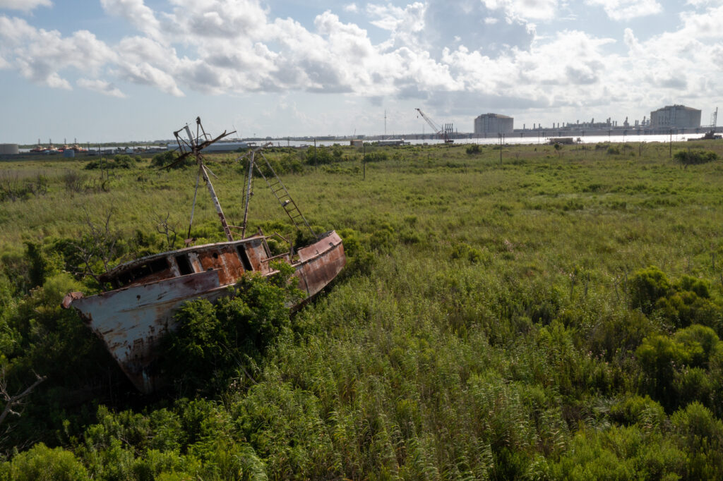 An abandoned fishing boat damaged during Hurricane Laura lies across the river from an expanding liquefied natural gas export terminal in Cameron Parish, La. Some local fisherman in the region claim the LNG facilities are dramatically impacting shrimp and other sea life they depend on for their livelihoods. (Jeffrey Basinger/Floodlight)