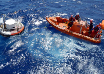 A small boat launched from a NOAA ship works to recover a Deep-ocean Assessment & Reporting of Tsunamis (DART) transponder buoy, part of the U.S. early tsunami detection system. (NOAA, Public domain, via Wikimedia Commons)