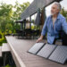 A man adjusts solar panels on his deck (iStock image)