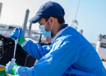 Luis Angel Nino Barreat works on a pier at the Marine Campus to prepare the liquid medium for the VIVAS device that collects Saharan dust samples. (Photo: Matthew Rembold/University of Miami)