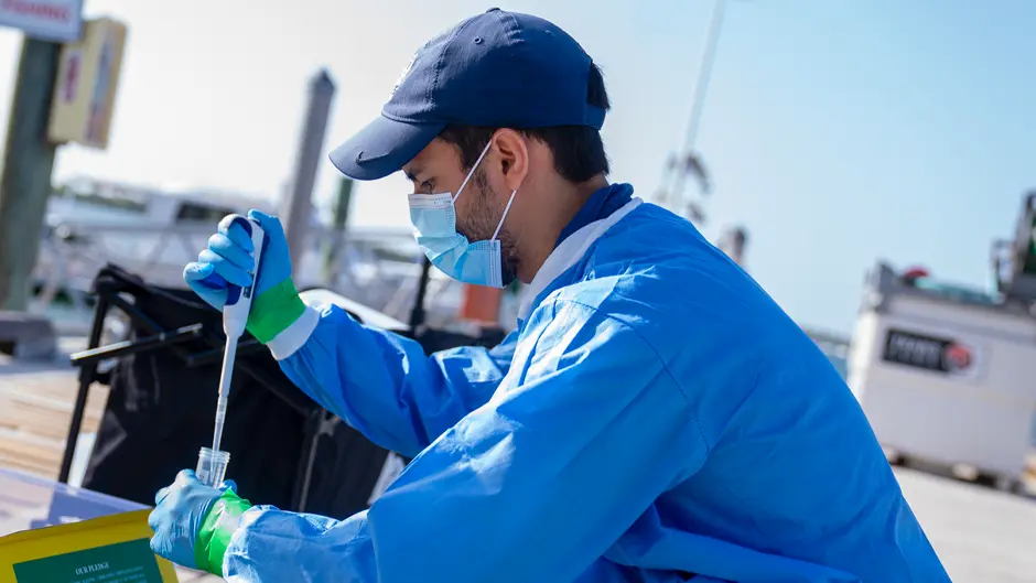 Luis Angel Nino Barreat works on a pier at the Marine Campus to prepare the liquid medium for the VIVAS device that collects Saharan dust samples. (Photo: Matthew Rembold/University of Miami)