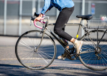 A woman rides a bike on city street. (iStock image)