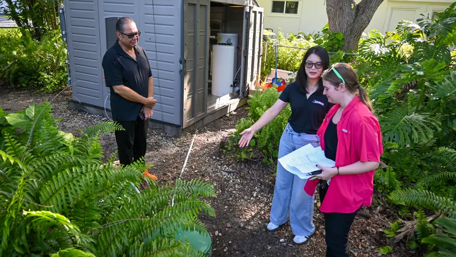 As Esber Andiroglu, left, looks on, Qiufeng Lin talks with Nancy Ham of the Florida Department of Environmental Protection about the EHM system. (Photo: Betsy Martinez/University of Miami)