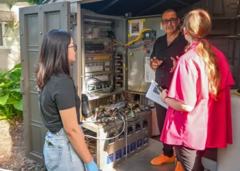 With Qiufeng Lin, left, looking on, Esber Andiroglu gives Nancy Ham of the Florida Department of Environmental Protection an update on the EHM system. (Photo: Betsy Martinez/University of Miami)