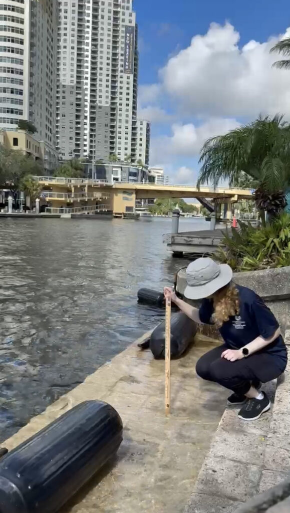 The author measures king tide levels in downtown Fort Lauderdale. (Screenshot of Broward County video)