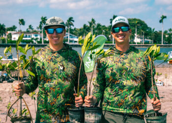Keith and Kyle Rossin wear mangrove camouflage while holding mangroves for planting. (Photo courtesy of MANG)