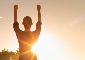 A woman holds her fists up to the sky (iStock image)