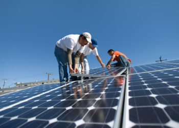 Workers install solar panels on a rooftop (iStock image)