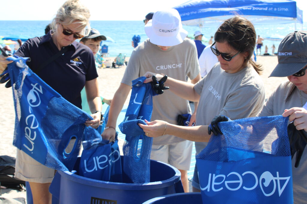 Volunteers pour out trash into a receptacle at a 4ocean beach cleanup Friday at Spanish River Park in Boca Raton. (Benjamin Mostow photo)