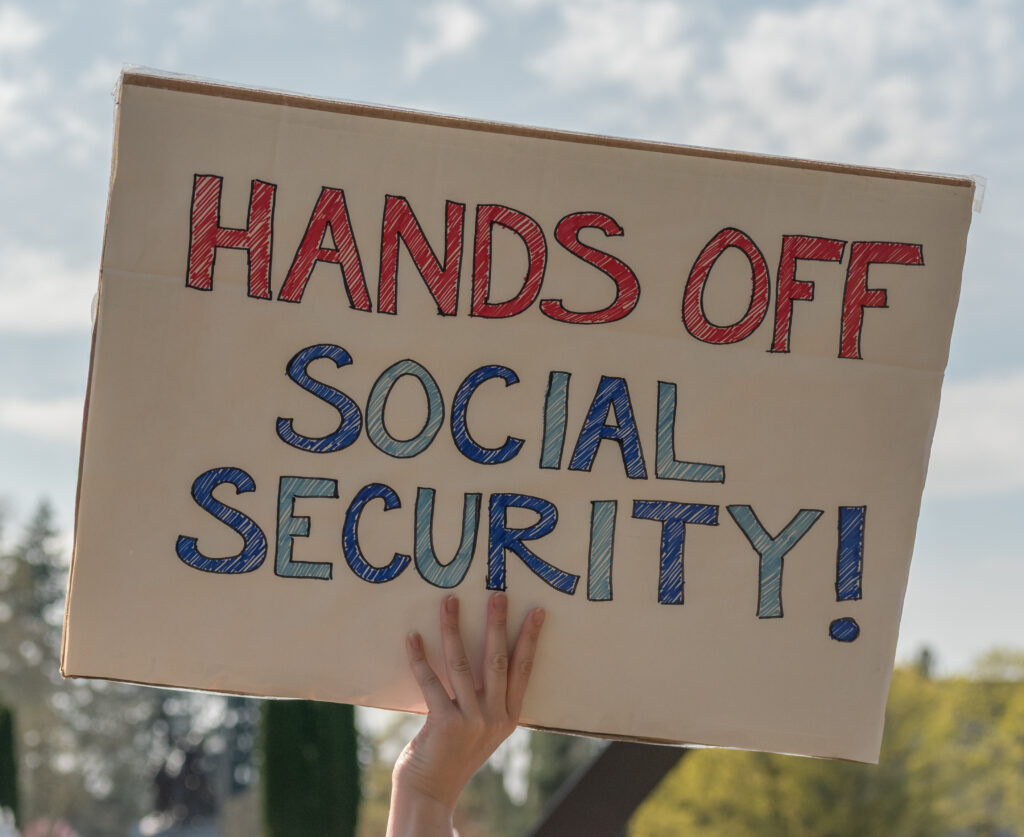 A sign protesting changes to Social Security at a rally in 2025. (Roc0ast3r, CC0, via Wikimedia Commons)