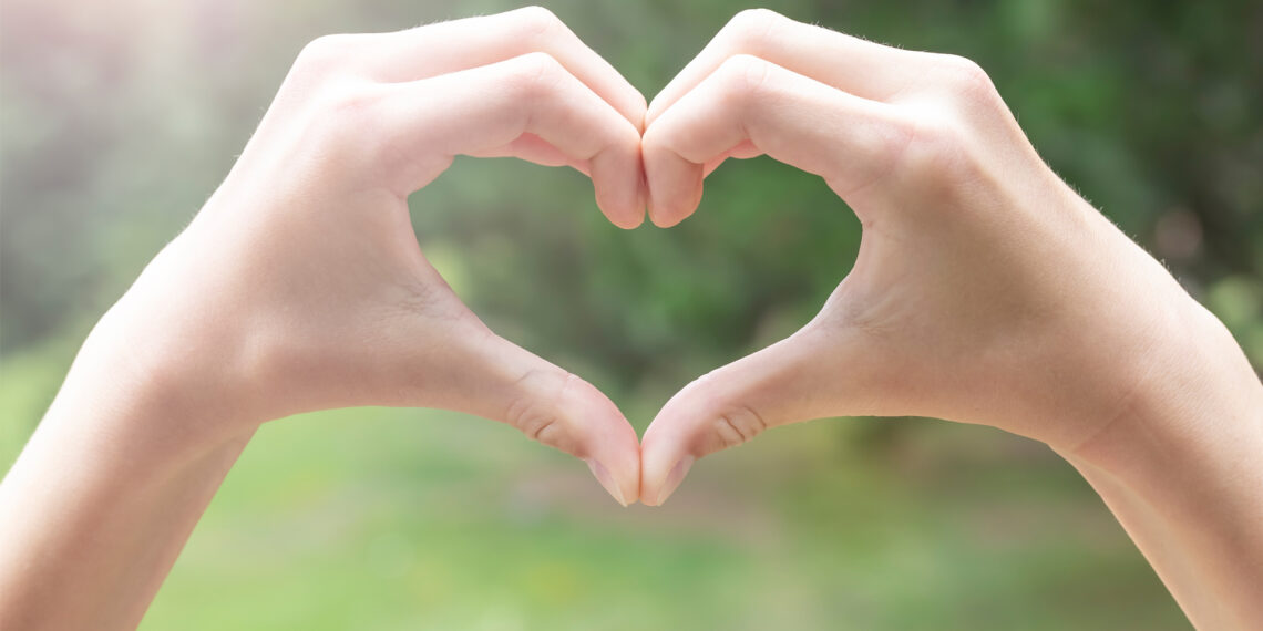 Hands in the shape of a heart against a forest background (iStock image)