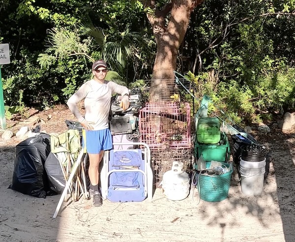 Andrew Otazo stands beside his trash haul after removing 'another 270 pounds of trash from the mangroves including (for some reason) six suitcases, three dog crates, one oven, one propane tank, and a blender.' (Andrew Otazo/Facebook)