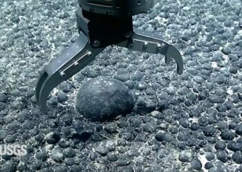 A metal claw reaches for an iron and manganese nodule on the seabed for testing. (USGS Pacific Coastal and Marine Science Center)