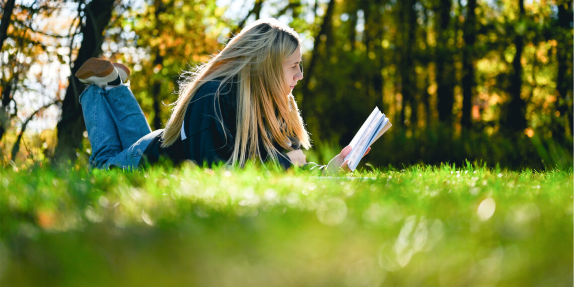 A woman reading a book in nature (iStock image)