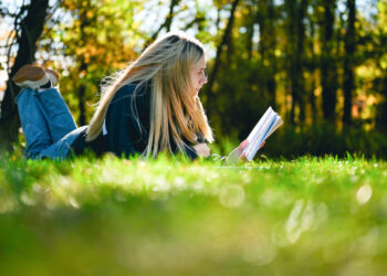 A woman reading a book in nature (iStock image)