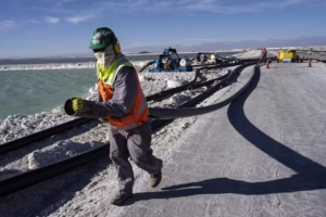Workers perform maintenance at pools where evaporation concentrates lithium-rich brine in Chile’s Atacama Desert in 2023. To extract lithium, mines pump water from beneath the salt flats. (AP Photo/Rodrigo Abd)