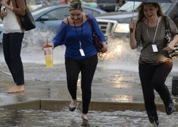 Pedestrians battle the wind, rain and flooded streets in downtown Denver. (Photo By John Leyba/The Denver Post via Getty Images)
